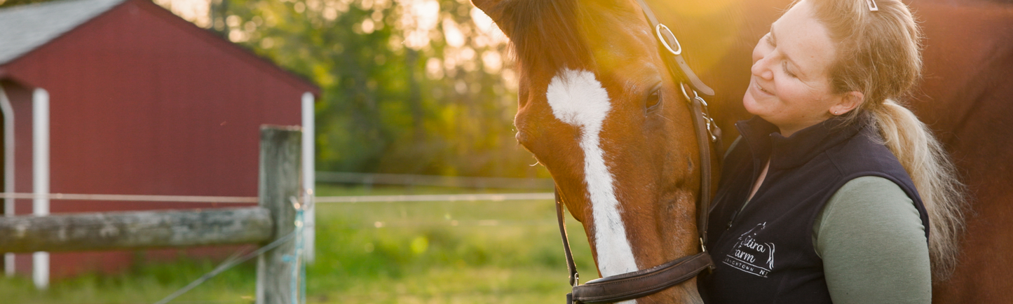A StableFeed client, Adrienne Meisner smiling and petting her horse's muzzle.