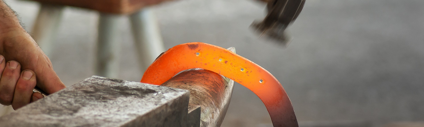 Farrier shaping horse shoe