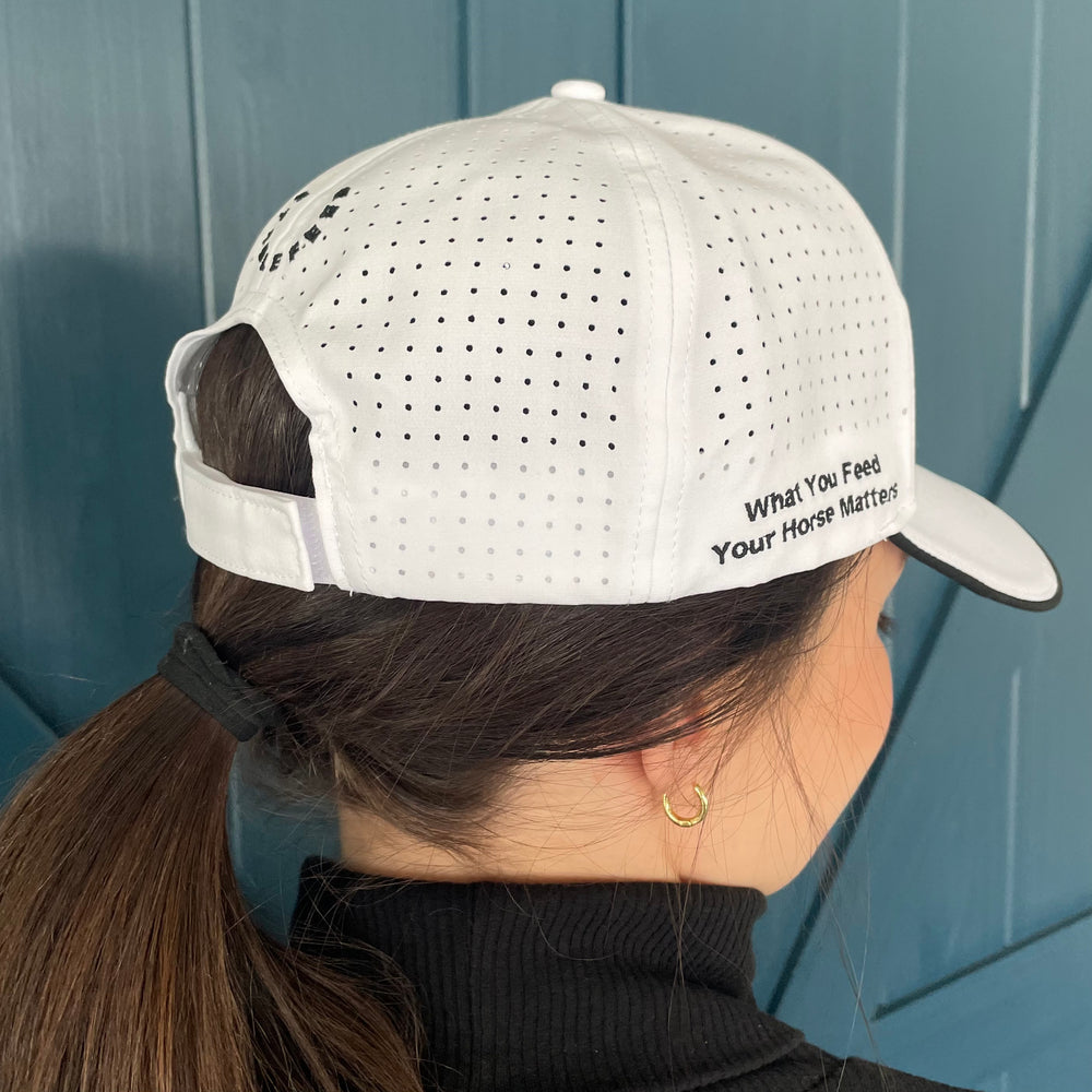 Backside of our white StableFeed cap with our logo over the back and What You Feed Your Horse Matters stitched on the right side. 