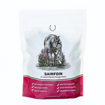 The Sainfoin Forage Pellet packaging is white with rich pink detailing, showing a horse and young girl happily together in a field of sainfoin.